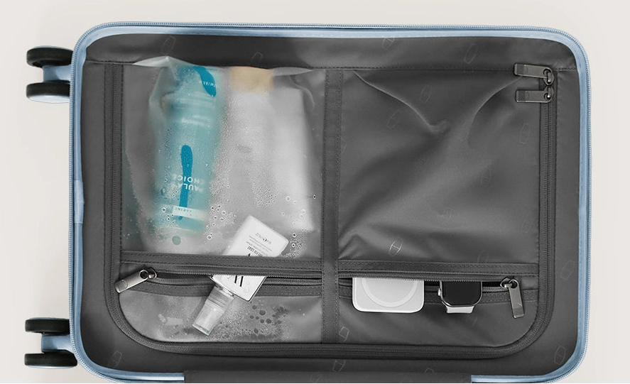Open suitcase with travel essentials including bottles and a bag on a light gray background